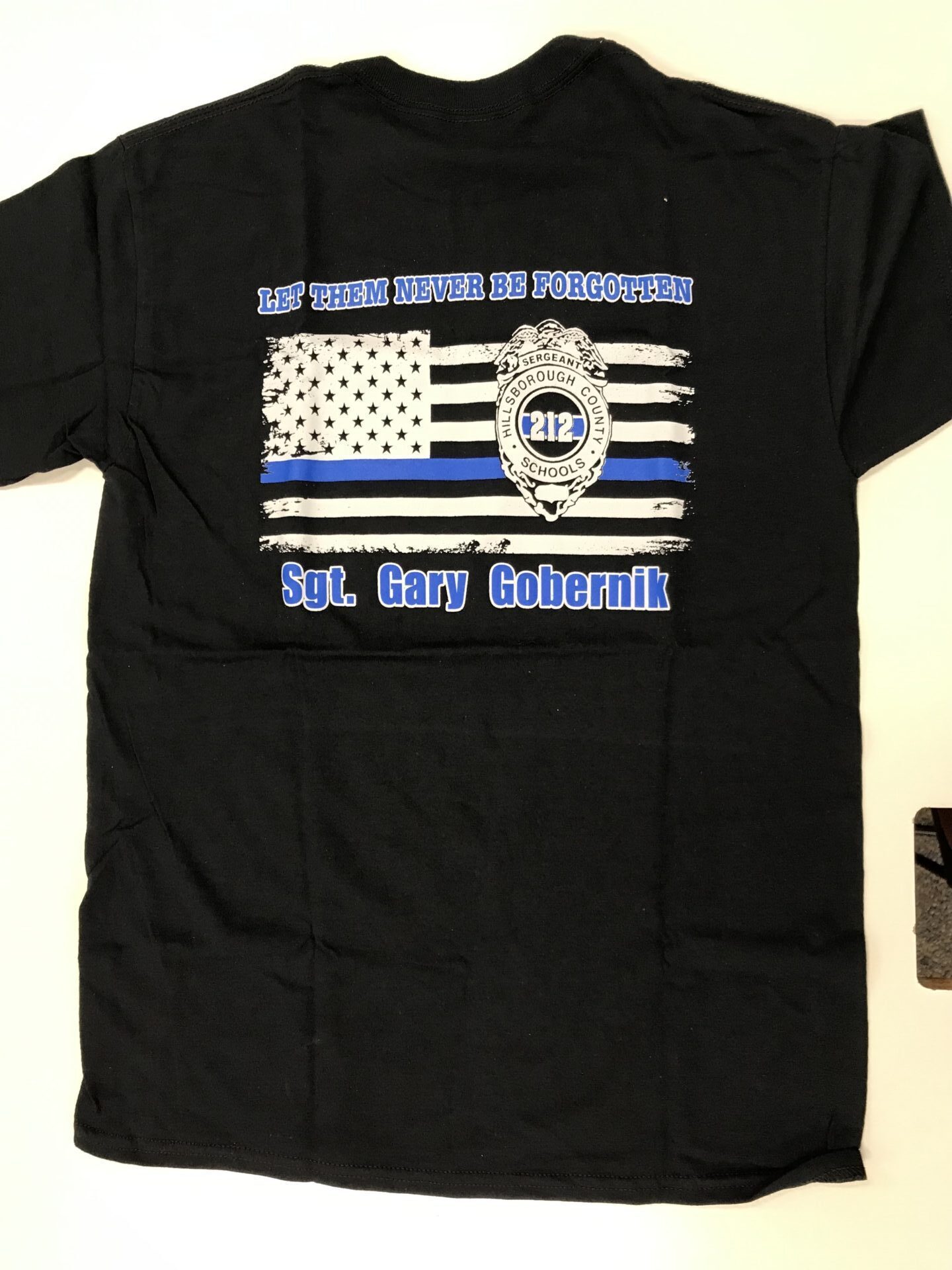 A black shirt with an american flag and police badge.