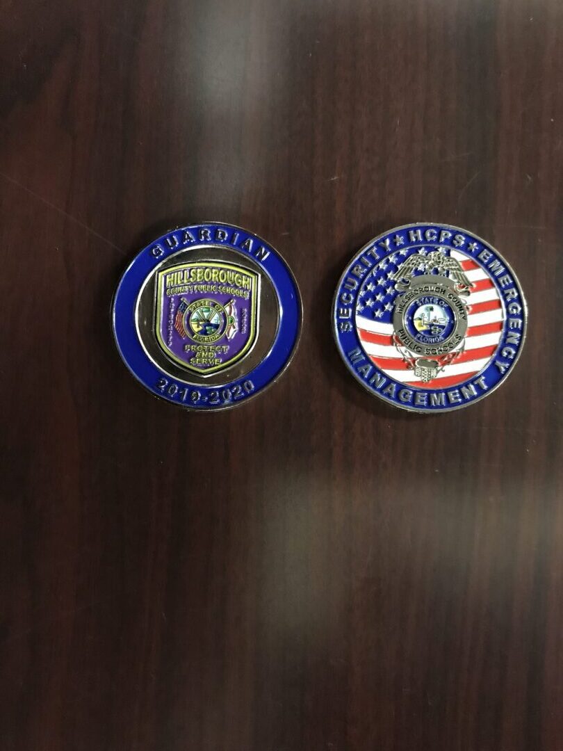 Two police badges sitting on top of a wooden table.