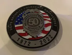 A coin with the words " 5 0 years of hps security emergency management."