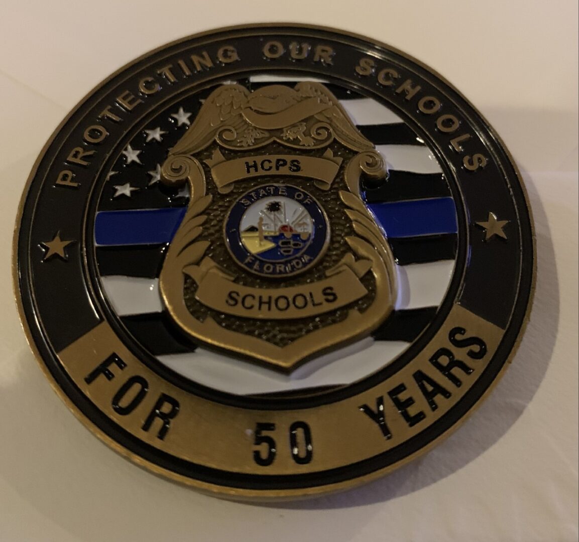 A police badge with the words protecting our schools for 5 0 years written on it.