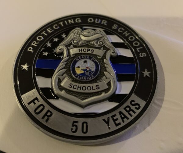 A police badge with the words protecting our schools for 5 0 years.